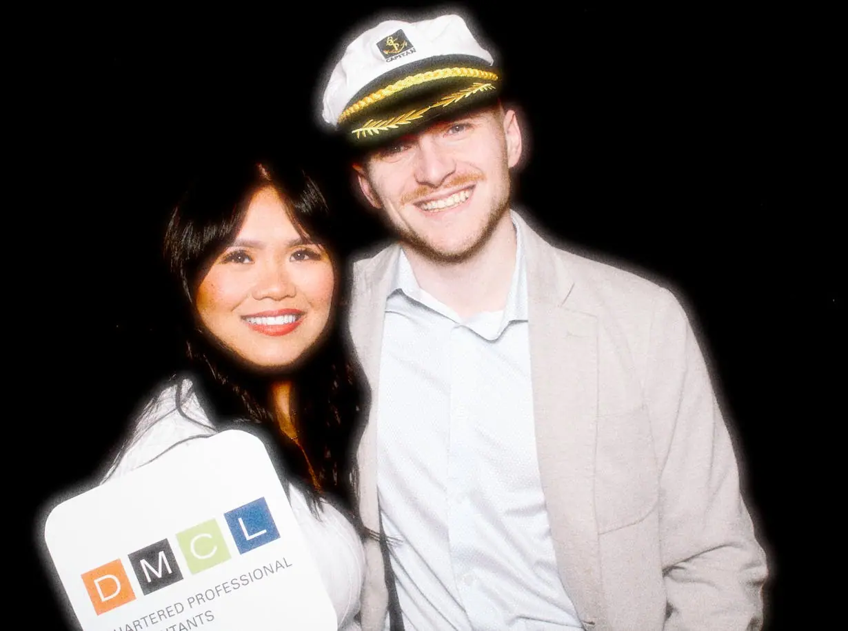A couple in a captain hat and a white blazer posing at the photo booth