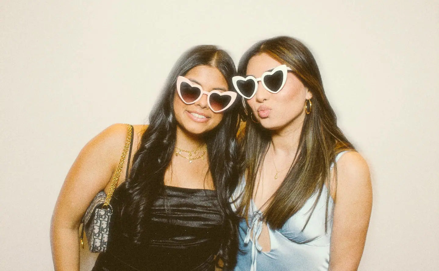 Two guests in black dresses with heart sunglasses at the photo booth