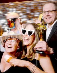 A group of friends and family posing in front of the photo booth for a private party