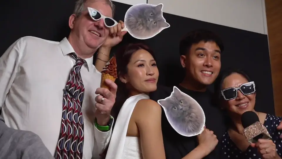 Wedding guests laughing with sunglasses and a cat-face prop in front of the Viva open-air photo booth