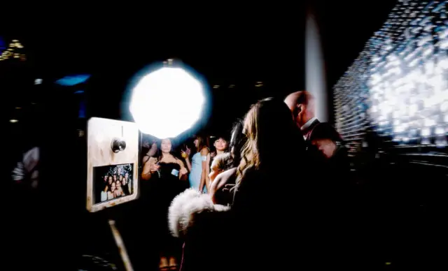 Guests lining up at the open-air booth under the studio light at a night party