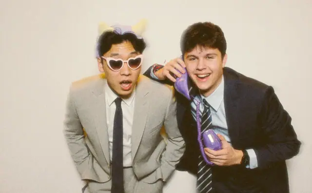 Two guests in suits goofing with ears and a phone prop