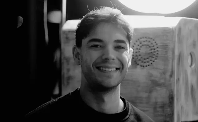 Smiling guest beside the wooden Viva booth, black and white