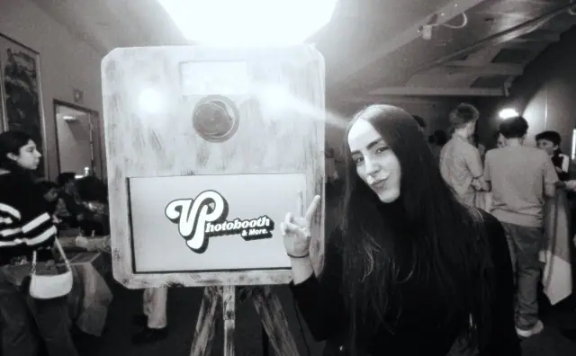 The wooden Viva booth with its logo and a guest beside it, black and white