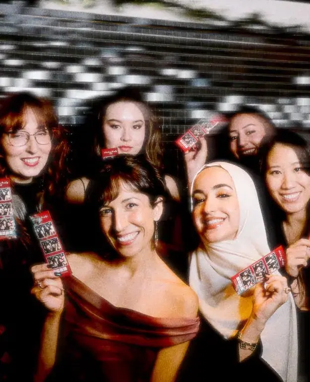 Friends holding their photo booth print strips at a party