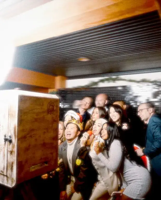 Crowd of guests packed in front of the wooden open-air photo booth at a venue