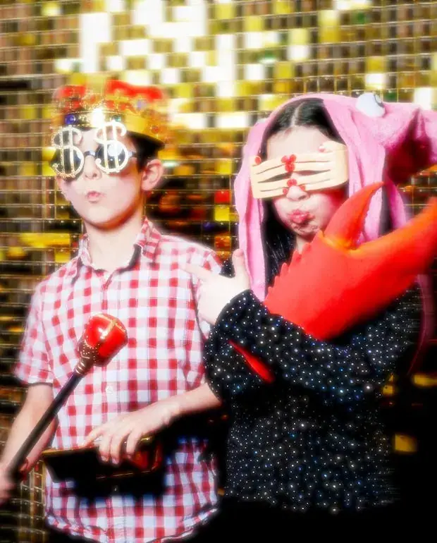 Two guests with inflatable props and party glasses on a gold sequin backdrop