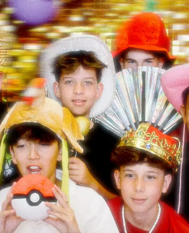 Kids in colourful party hats and props crowded into one booth shot