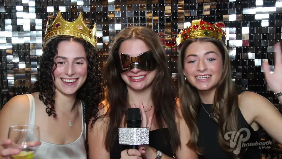 Guests recording video messages with a sparkly microphone in front of a sequin wall